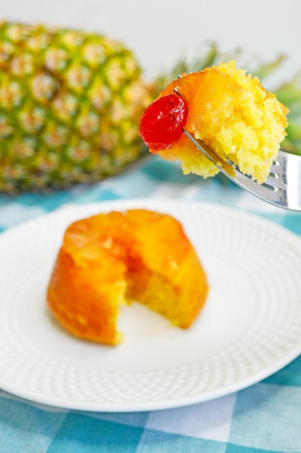 a bite of mini pineapple upside down cake with a cherry on a fork.
