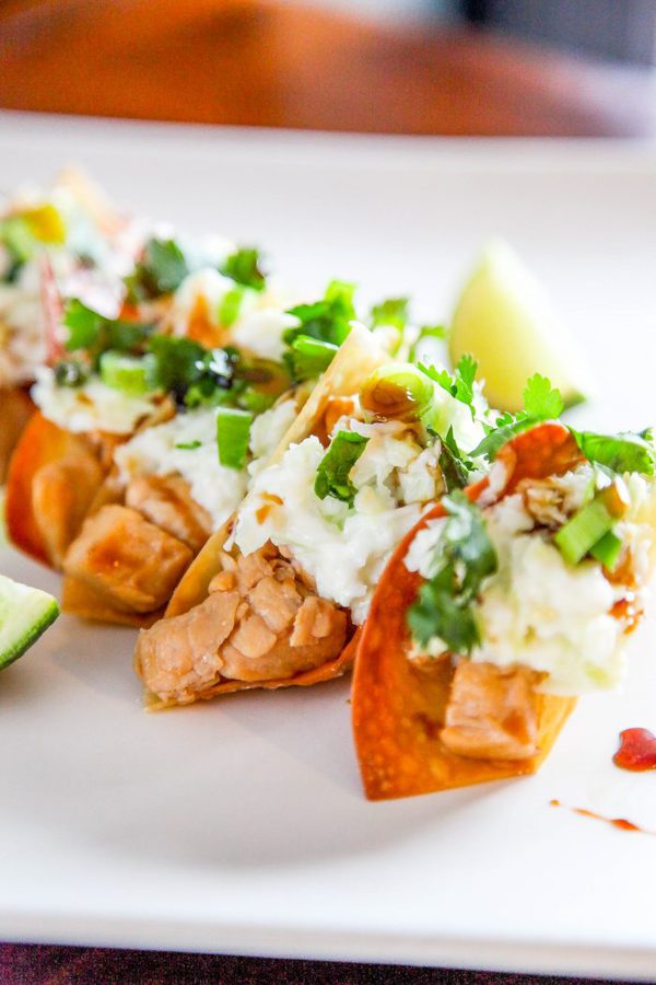 chicken wonton tacos topped with cabbage slaw, green onions, and cilantro. 