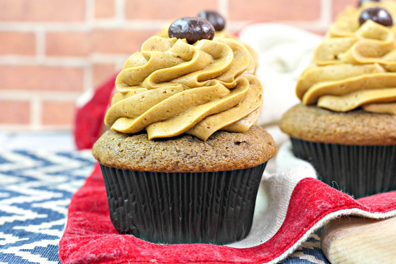 chocolate cupcakes filled with chocolate ganache and topped with coffee frosting on a red tea towel. 
