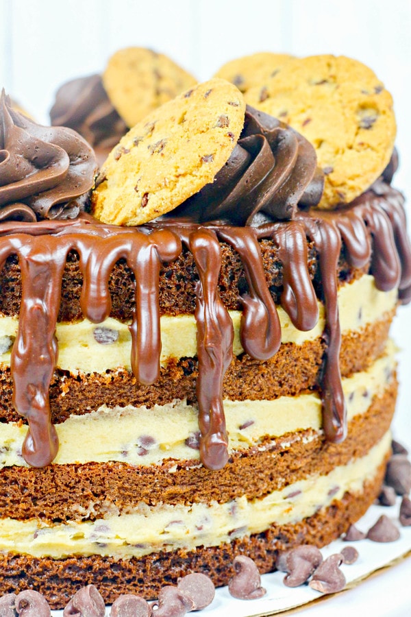 a side view of a chocolate cake with cookie dough filling, chocolate frosting, and a ganache drizzle.