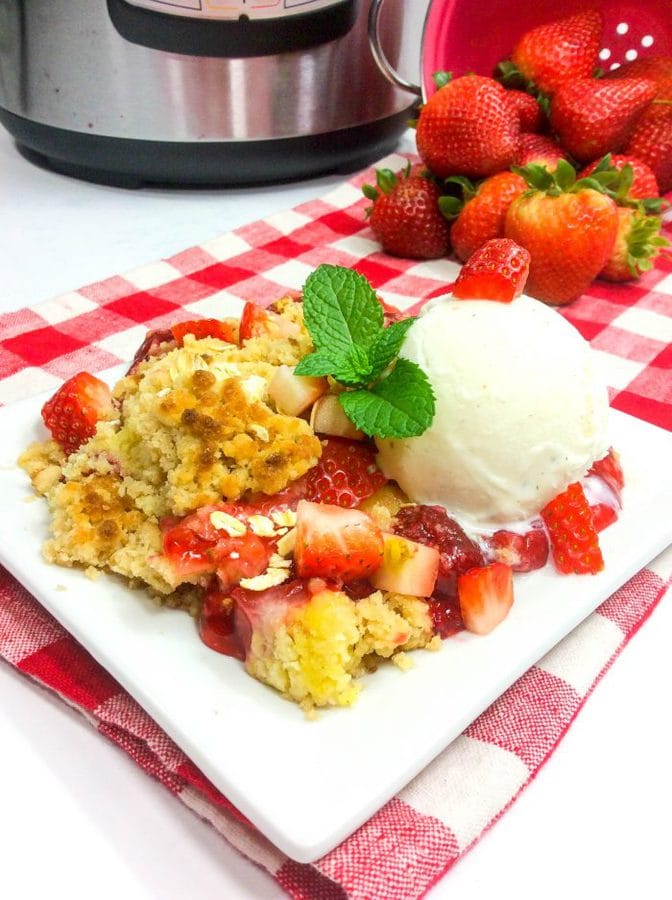 a strawberry dump cake on a checkered tablecloth with fresh strawberries and an instant pot in the background.