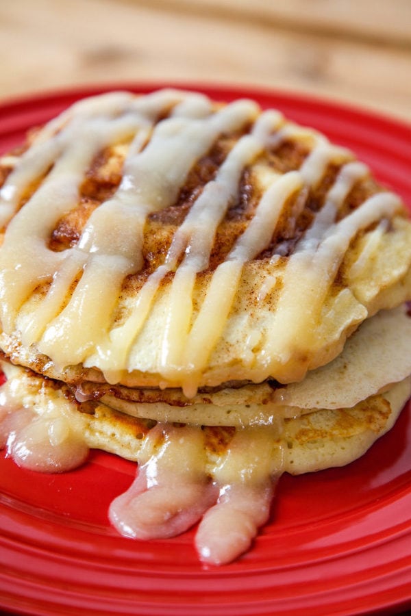a stack of three cinnamon pancakes drizzled with a cream cheese glaze. 