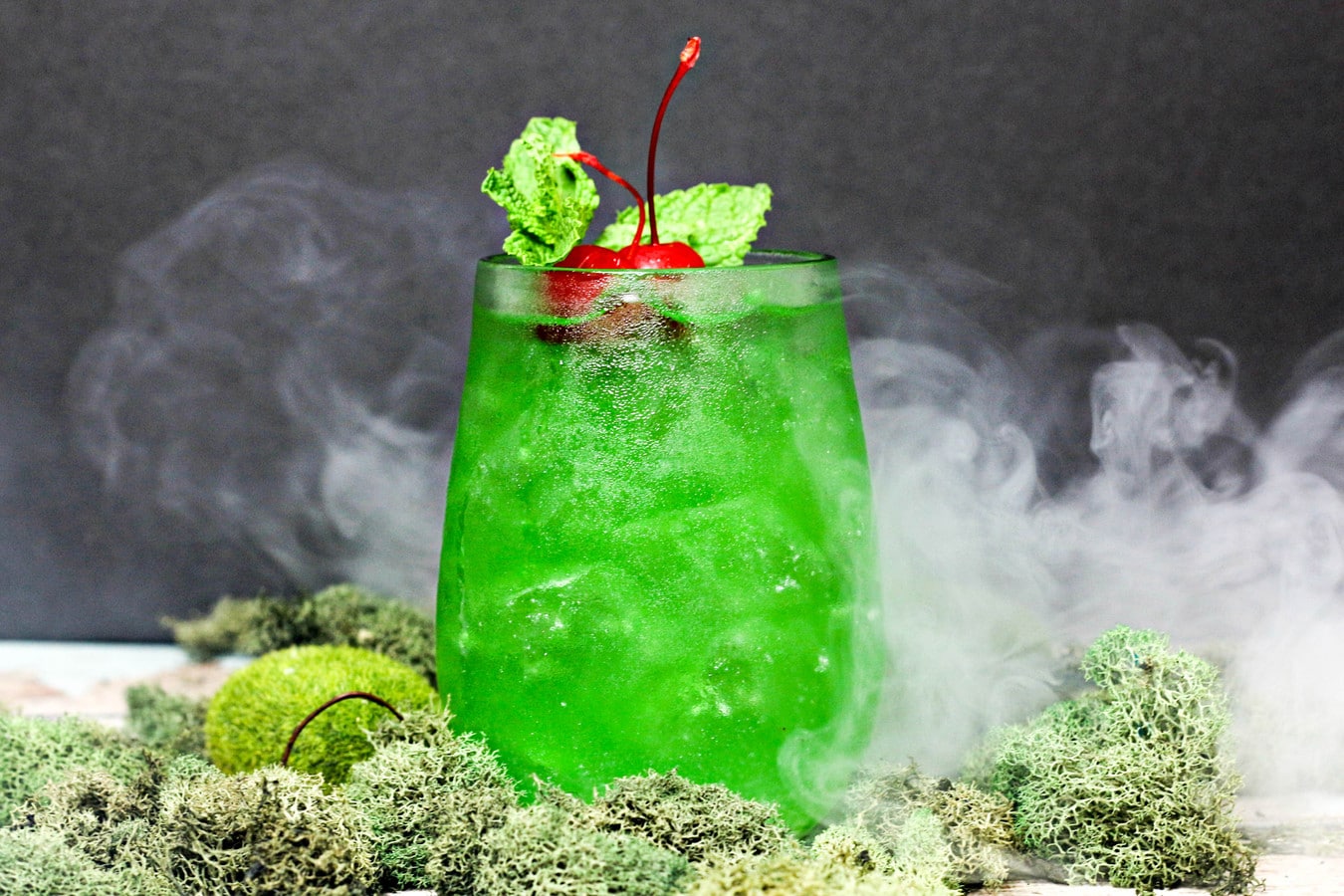 a horizontal image of a green drink with smoke in the background.