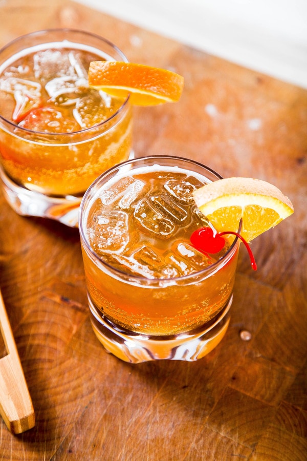 2 amaretto sour cocktails garnished with an orange wedge and a cherry.