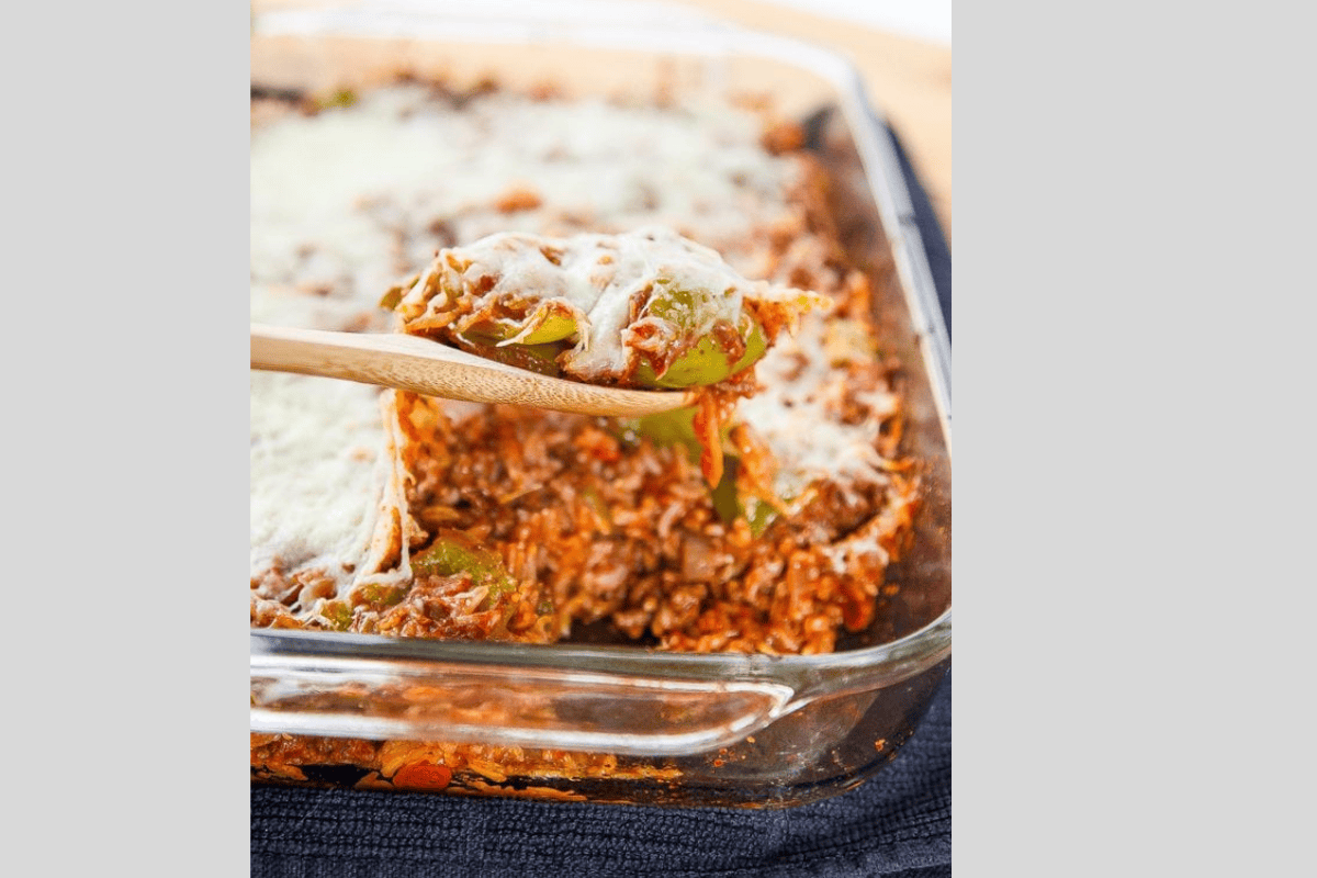 A spoon lifting out stuffed pepper casserole topped with mozzarella cheese.