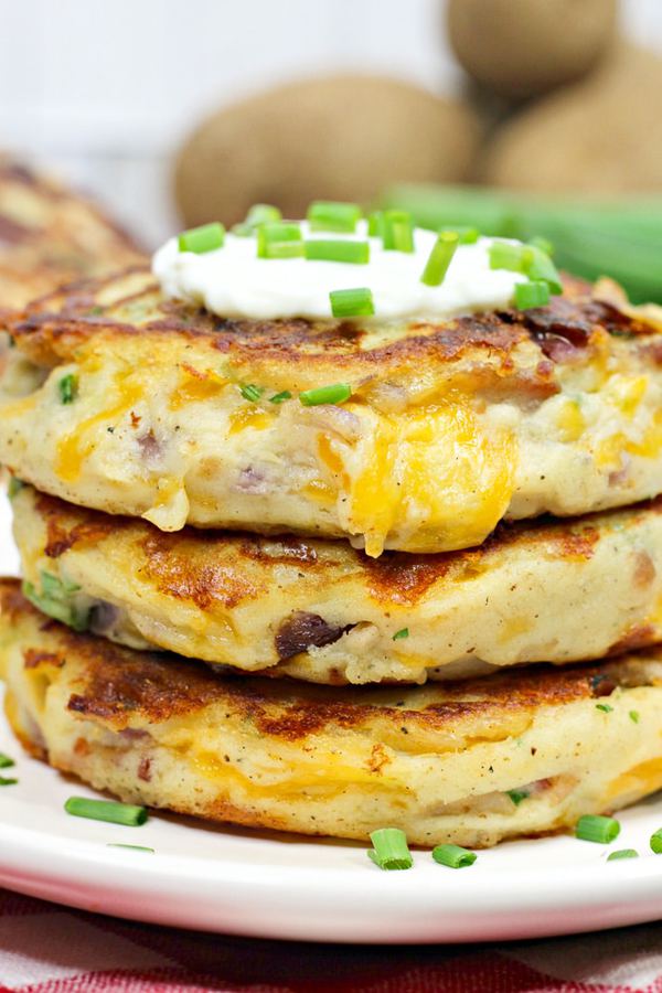 three pan fried mashed potato cakes topped with sour cream and chives.
