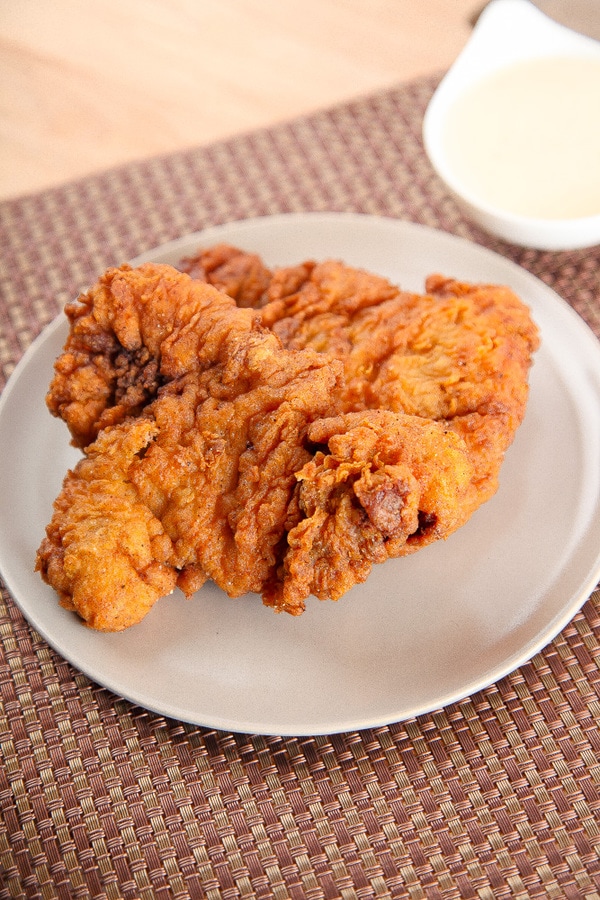 Chicken Fried Steak on an off white plate with a bamboo placement.