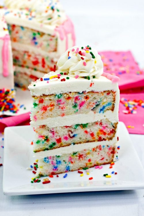 a slice of funfetti cake topped with vanilla buttercream and sprinkles.