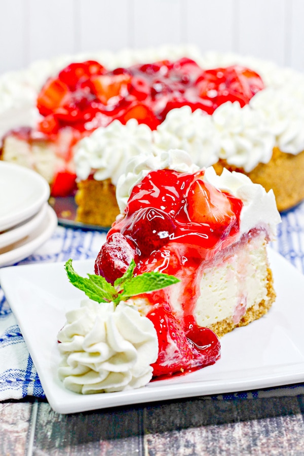 a slice of cheesecake topped with a strawberry sauce and garnished with whipped cream.