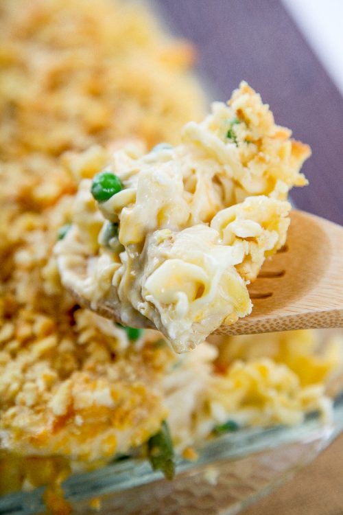 a wooden slotted spoon with chicken noodle casserole on it.