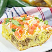 a casserole filled with eggs and chorizo and topped with tomatoes and cilantro on a white plate.