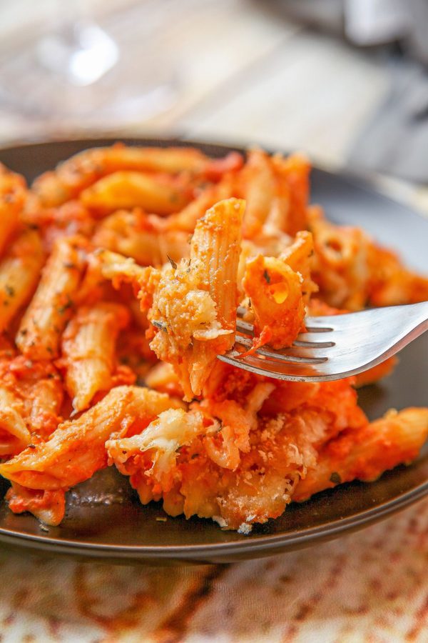 A close up image of penne pasta, sauce, and bread crumbs.
