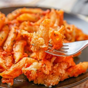 a close up image of penne pasta, sauce, and bread crumbs.