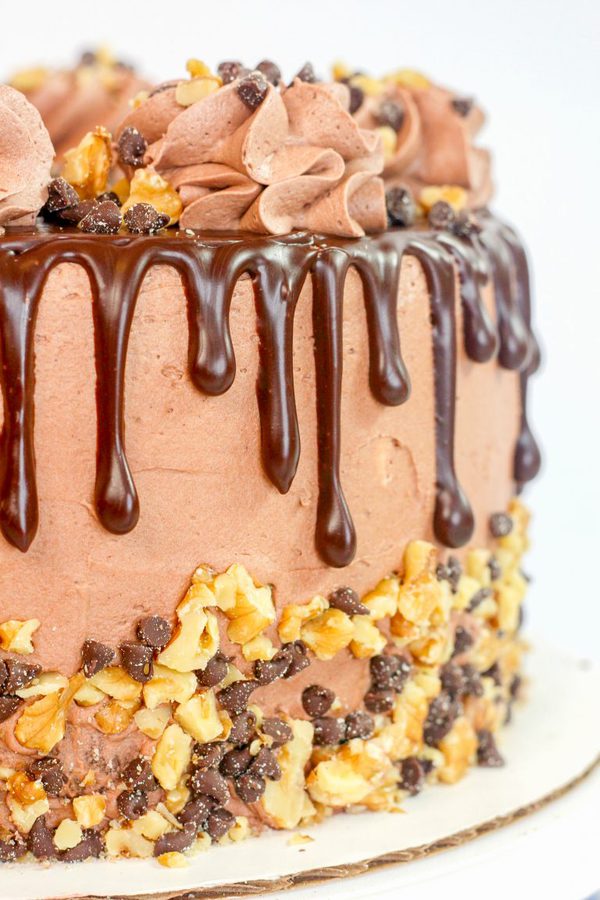 a chocolate cake with dripping ganache, walnut, chocolate chips, and chocolate frosting