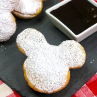 a mickey mouse shaped beignet on a black napkin.