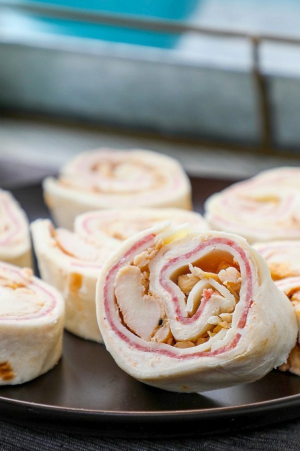 A close up of a tortilla roll up with chicken, salami and cheese.