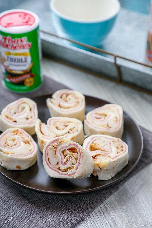 tortilla roll ups with meat, cheese, and olive salad on a black plate.