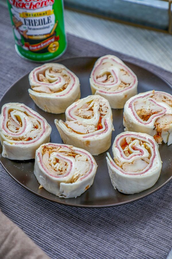 a black plate full of muffuletta tortilla rollups
