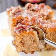 a form cutting into a pecan cake topped with praline sauce.