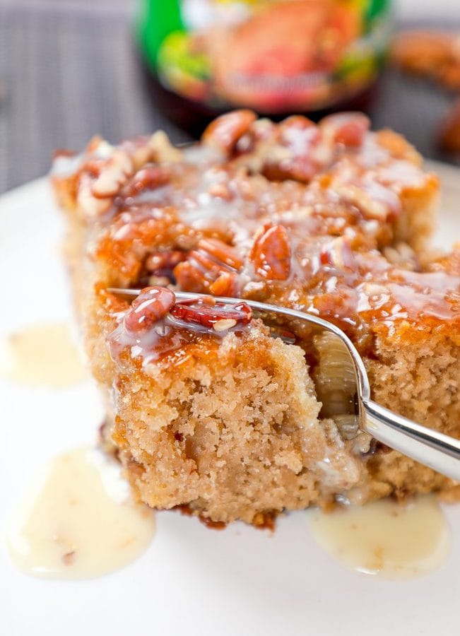 a form cutting into a pecan cake topped with praline sauce.