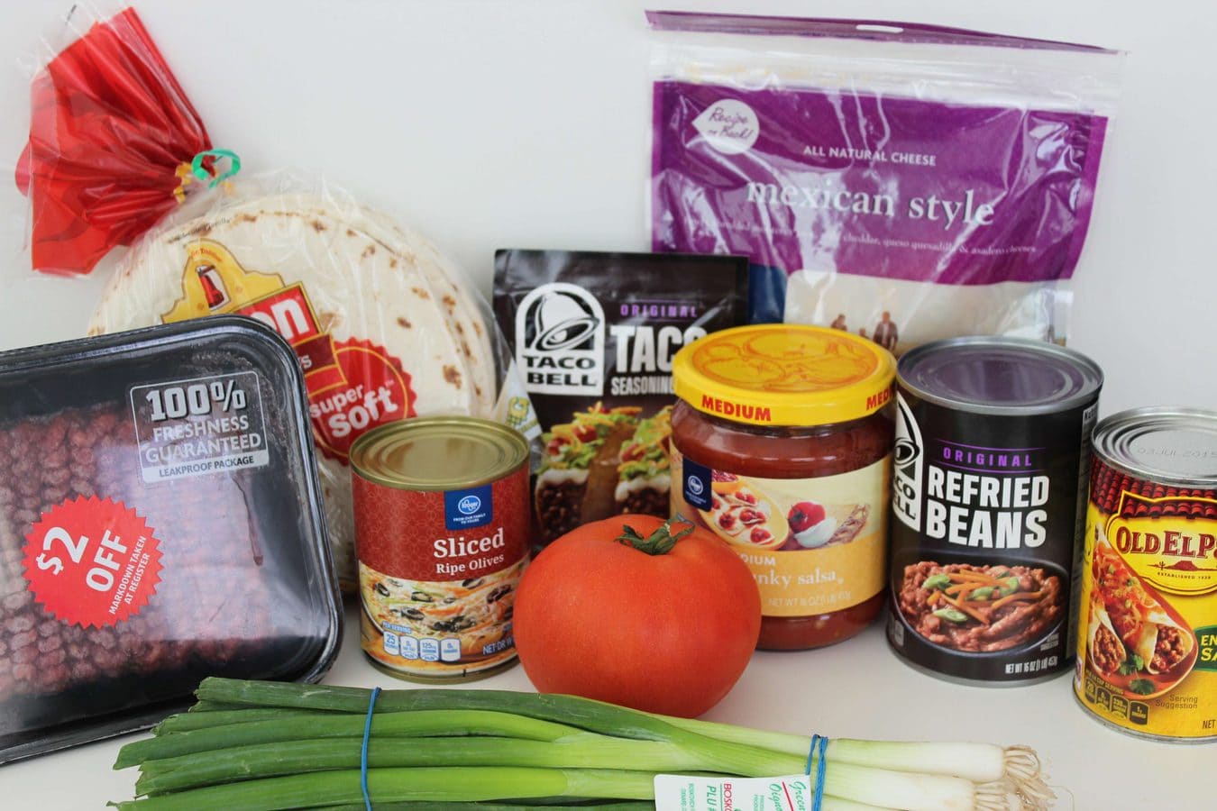 the ingredients needed to make a mexican pizza including beef, beans, and tortillas. 