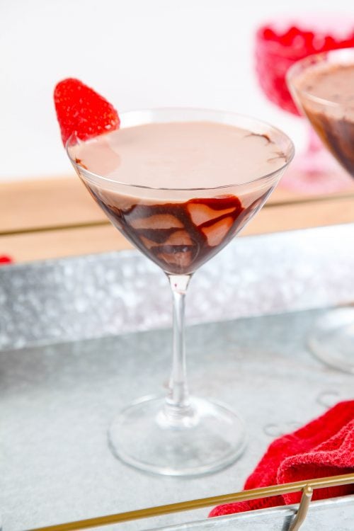 a chocolate cocktail in a martini glass drizzled with chocolate syrup. 