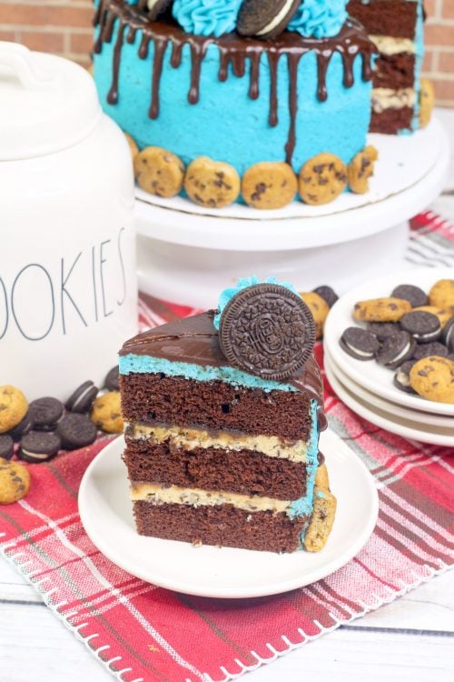 a slice oc cake with cookie dough frosting, blue oreo buttercream, and chocolate ganache.