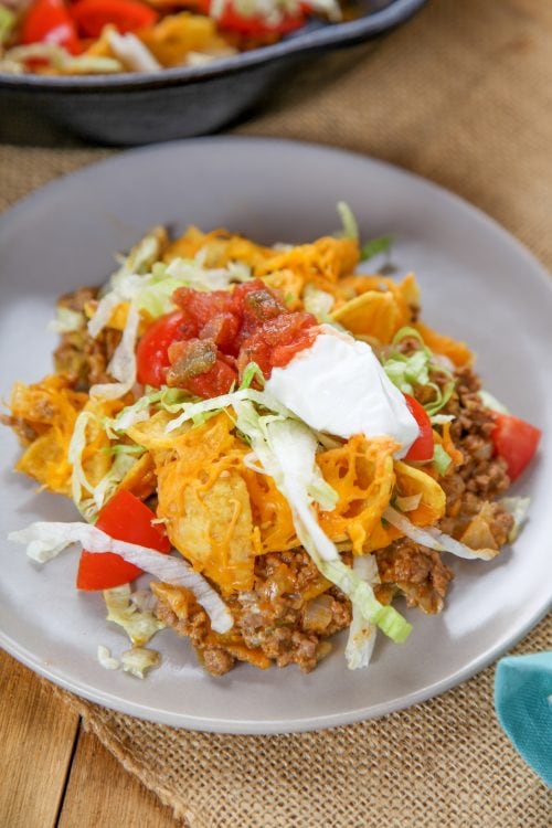an overheat view of a frito taco casserole with lettuce, salsa, and sour cream.