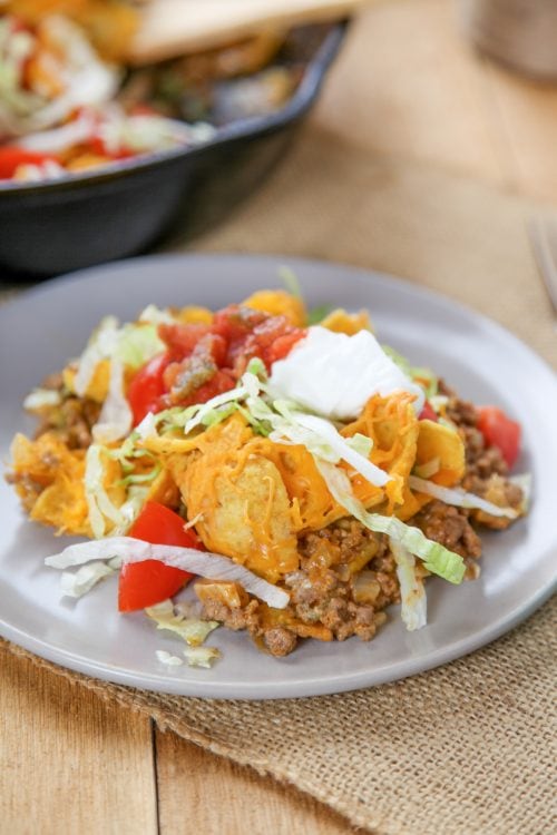 a walking taco casserole topped with lettuce, tomato,sour cream, and Fritos.