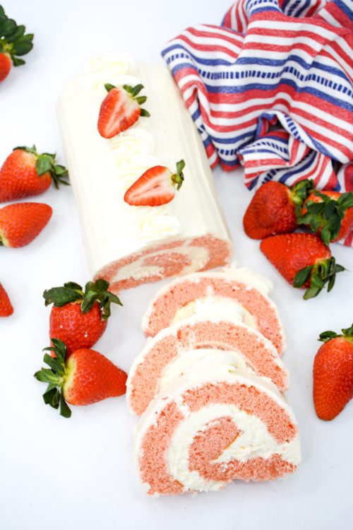 a strawberry cake roll filled and topped with cream cheese icing and fresh strawberries.