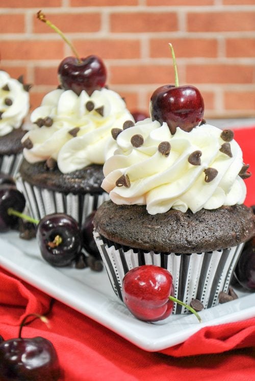 black forest cupcakes topped with vanilla buttercream, mini chocolate chips, and fresh cherries.