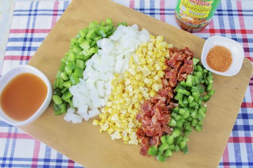 bell pepper, onion, corn, bacon, and jalapeno on a wooden cutting board.