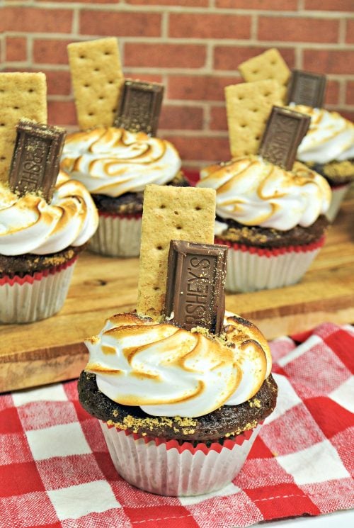 Smores cupcakes garnished with graham crackers and a hershey bar.