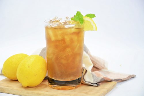 a long island iced tea on a cutting board with lemons and a tea towel.