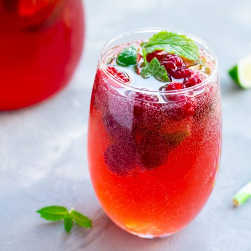 a bubbly raspberry cocktail topped with fresh berries and mint. 