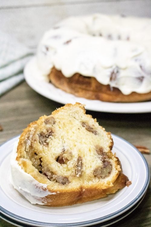 a slice of coffee cake with pecan filling and a cream cheese glaze.