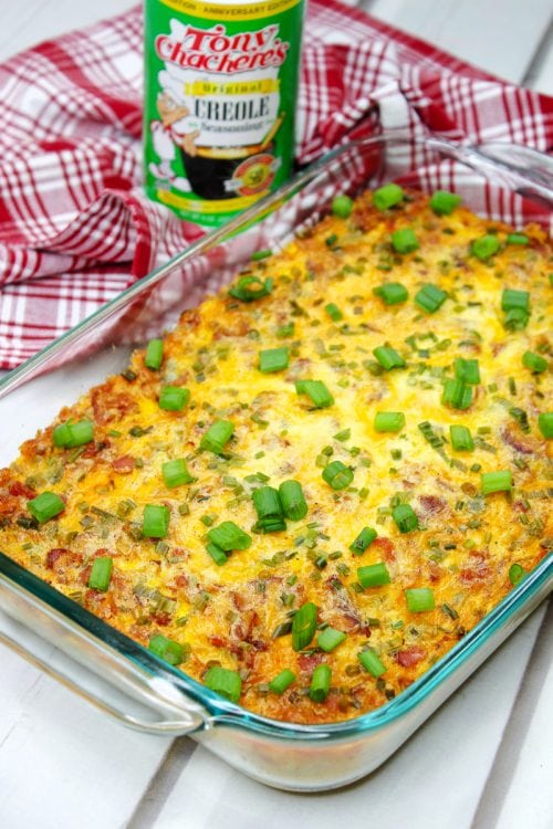 spoon bread casserole topped with green onions with a red and white towel in the background.