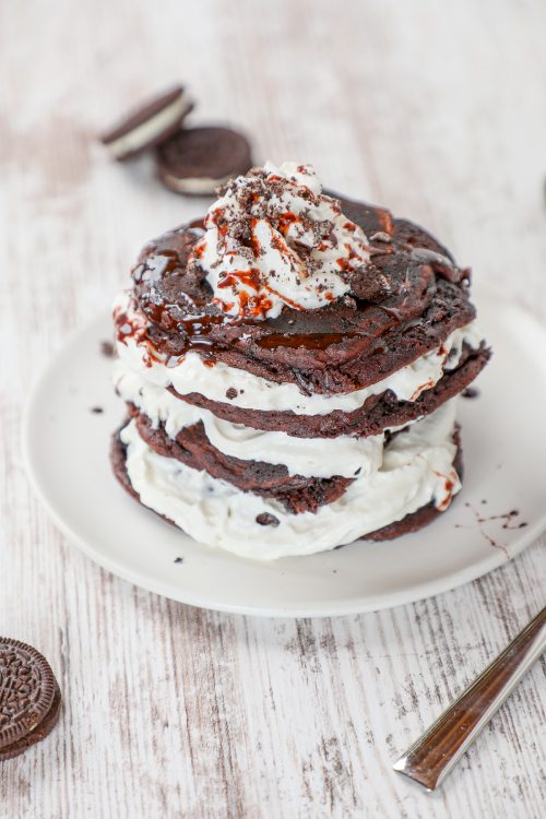 oreo pancakes with sweetened whipped cream on a white plate. 