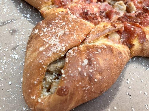 a corner of the four quarter calzony dusted with parmesean cheese