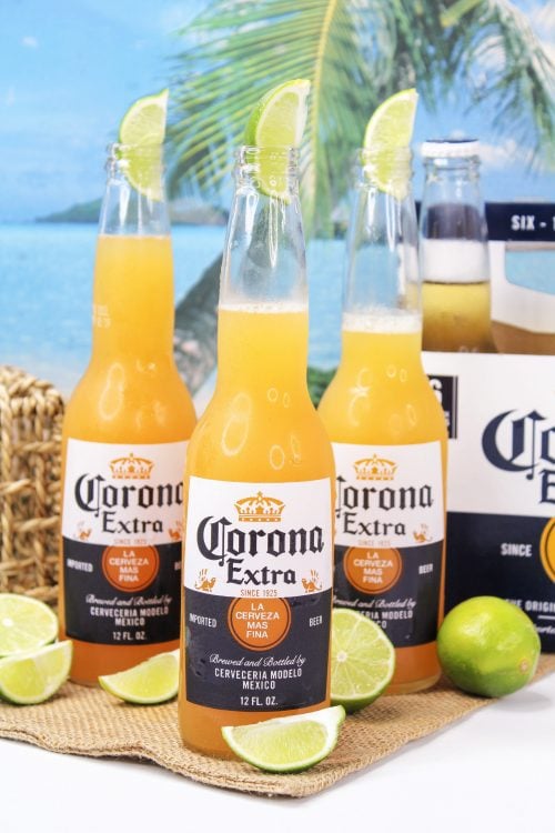 three corona beer bottles filled with a corona sunrise cocktail. 