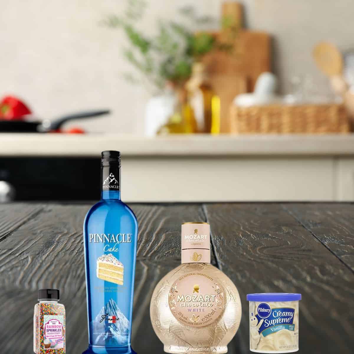 cake vodka, white chocolate liquor, sprinkles, and frosting on a wooden counter. 
