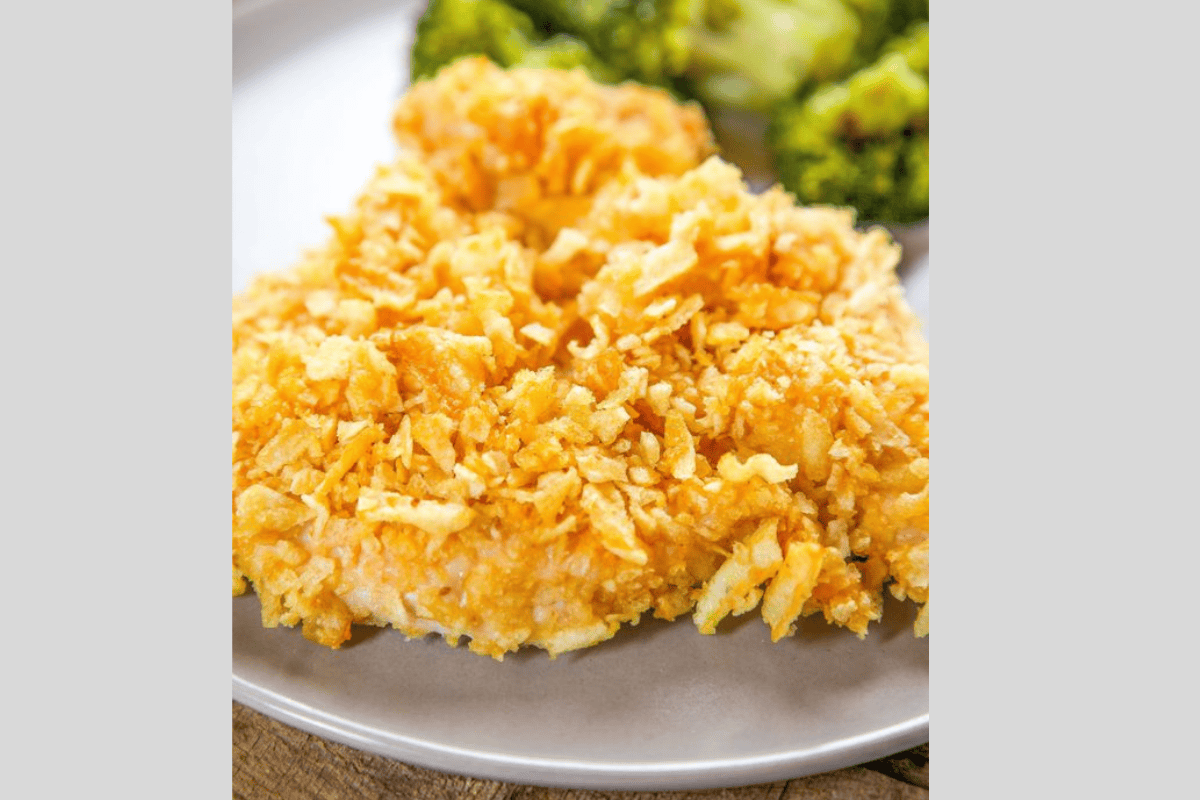 Chicken crusted with potato chips on a plate with broccoli.