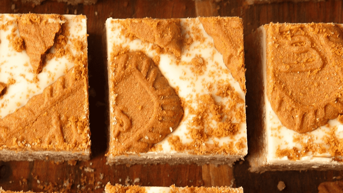 Squares of marshmallow treats with a thick frosting and Biscoff cookie chunks.
