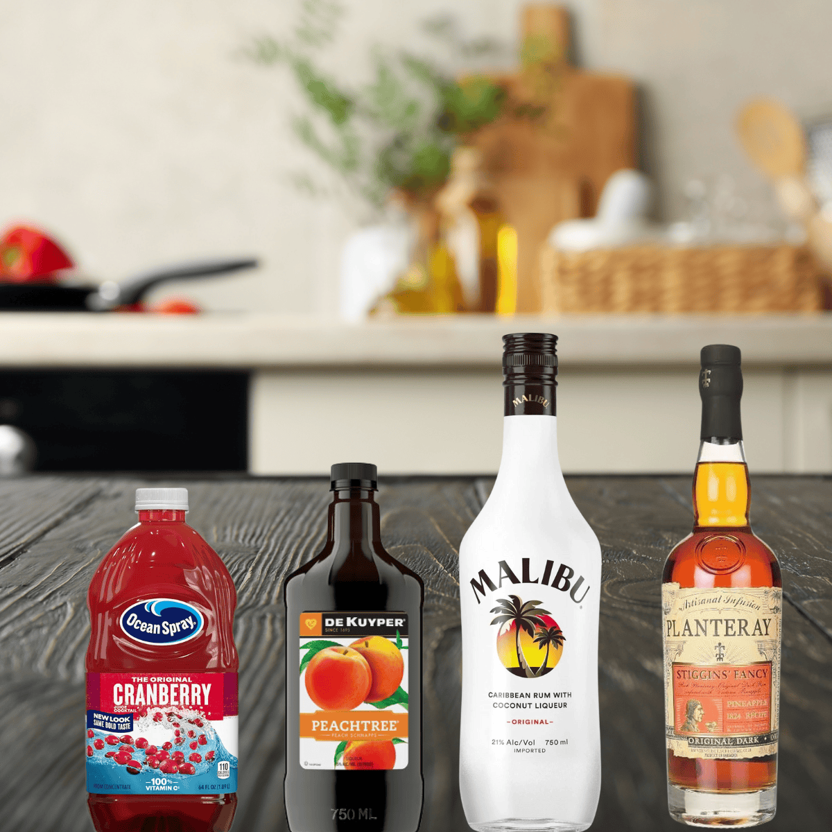 cranberry juice, peach schnapps, malibu rum, and  pineapple rum on a counter. 