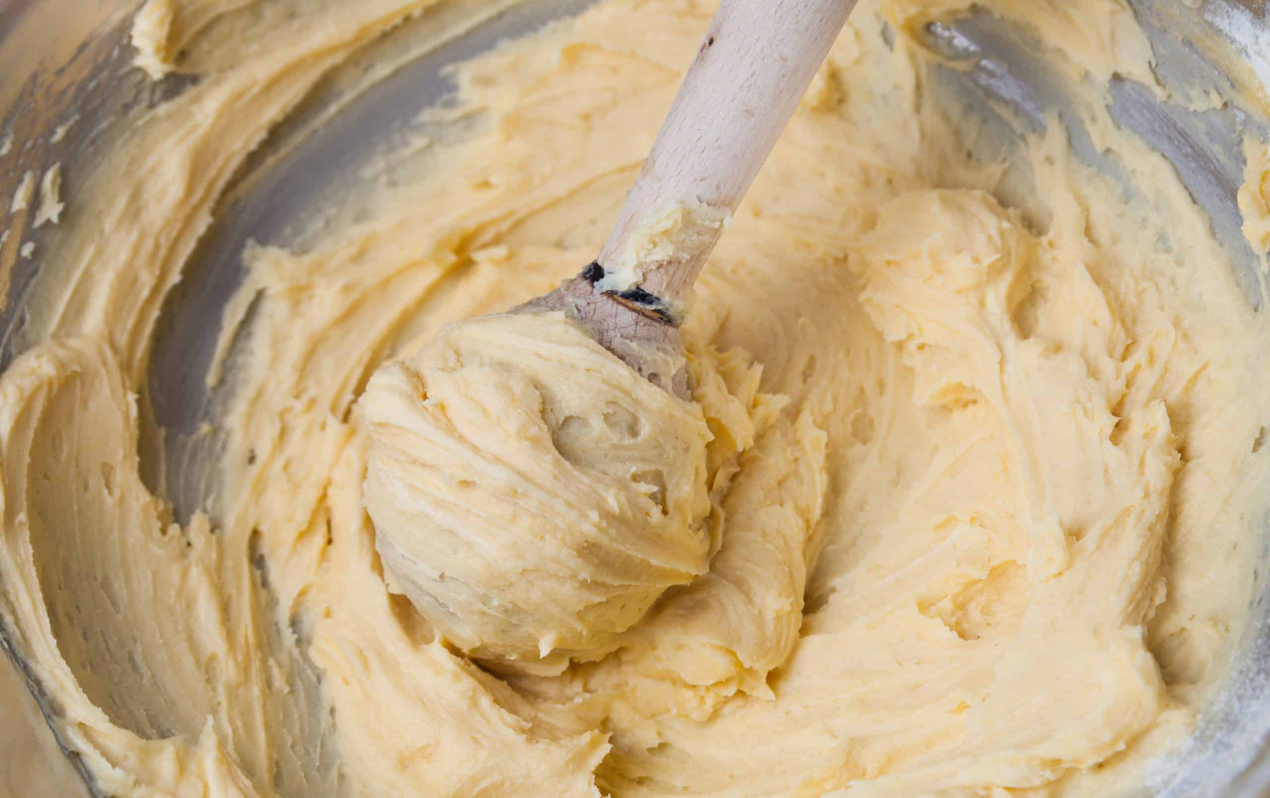zeppole batter in a bowl with a wooden spoon.