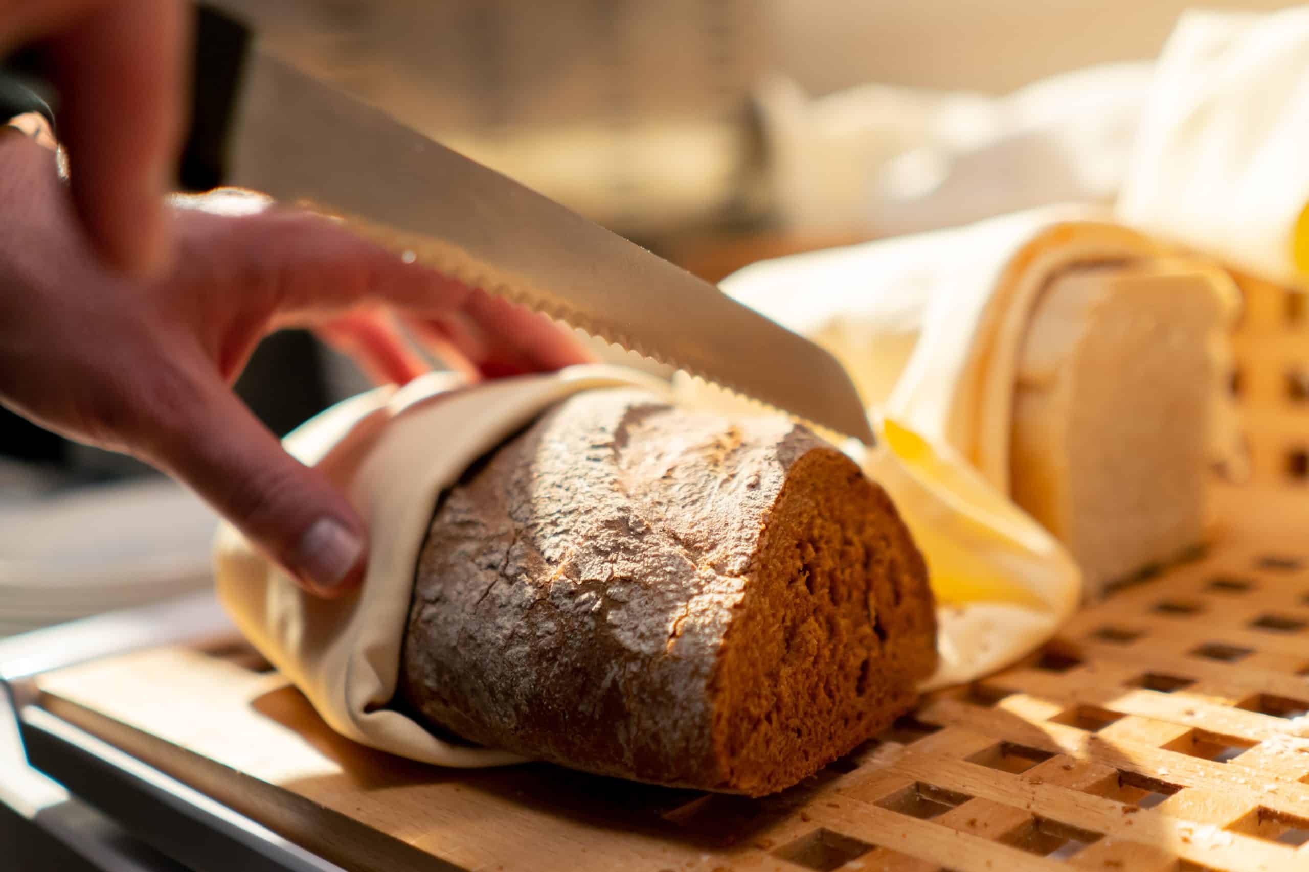 a buffet line in a hotel restaurant a guest cuts bread with knife during continental breakfast