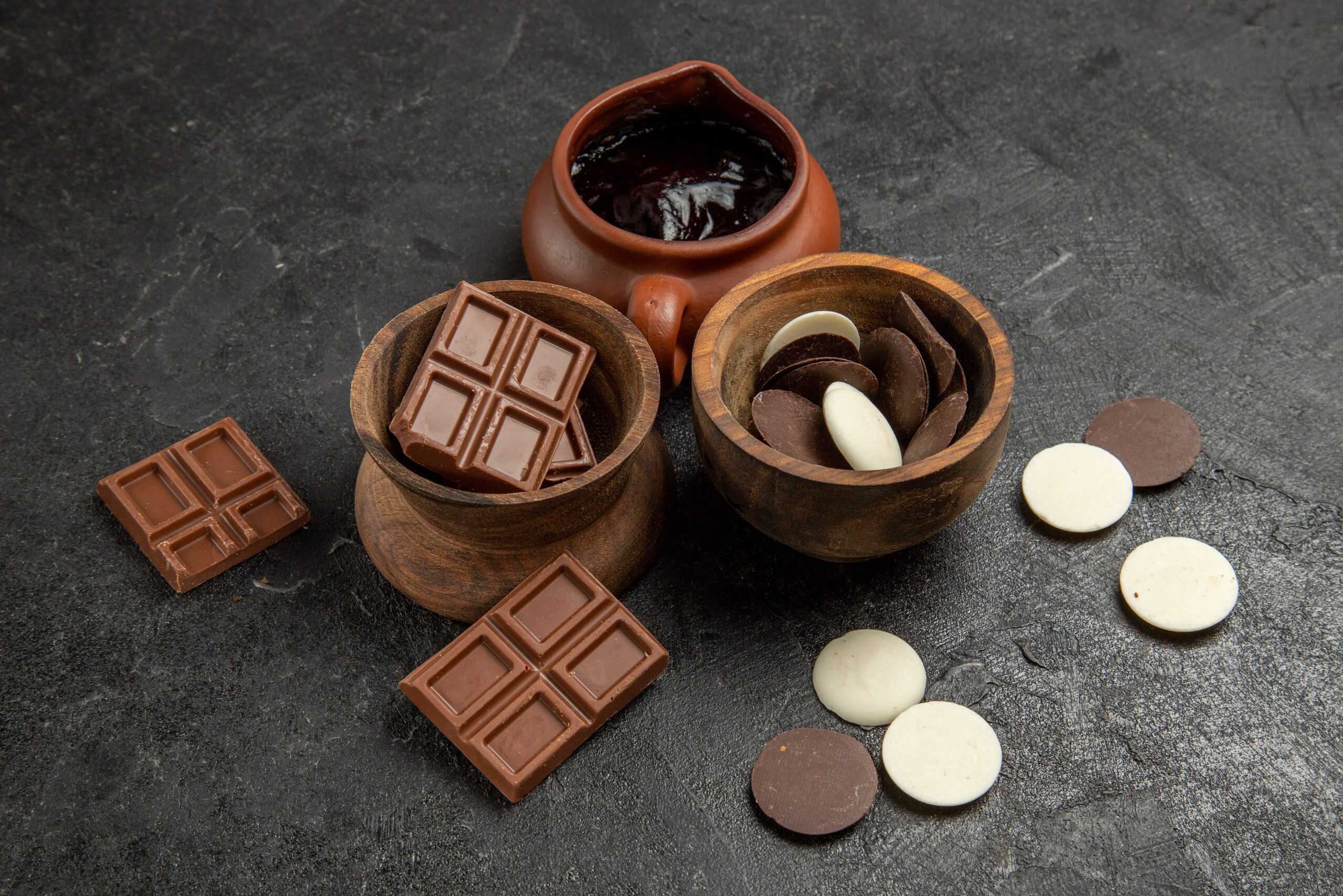 side close-up view chocolate chocolate and chocolate sauce in the bowls on the black table
