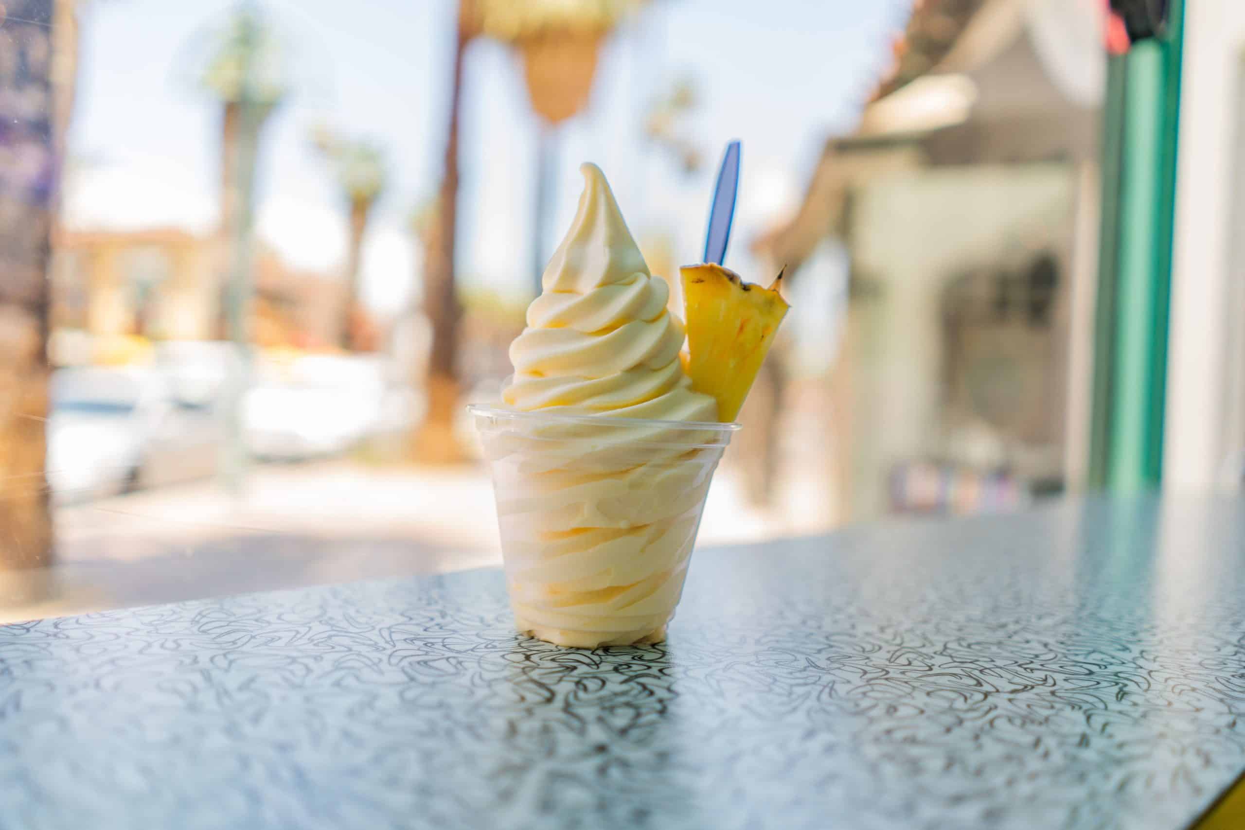 A pineapple dole whip frozen yogurt ice-cream with a pineapple wedge on a countertop.