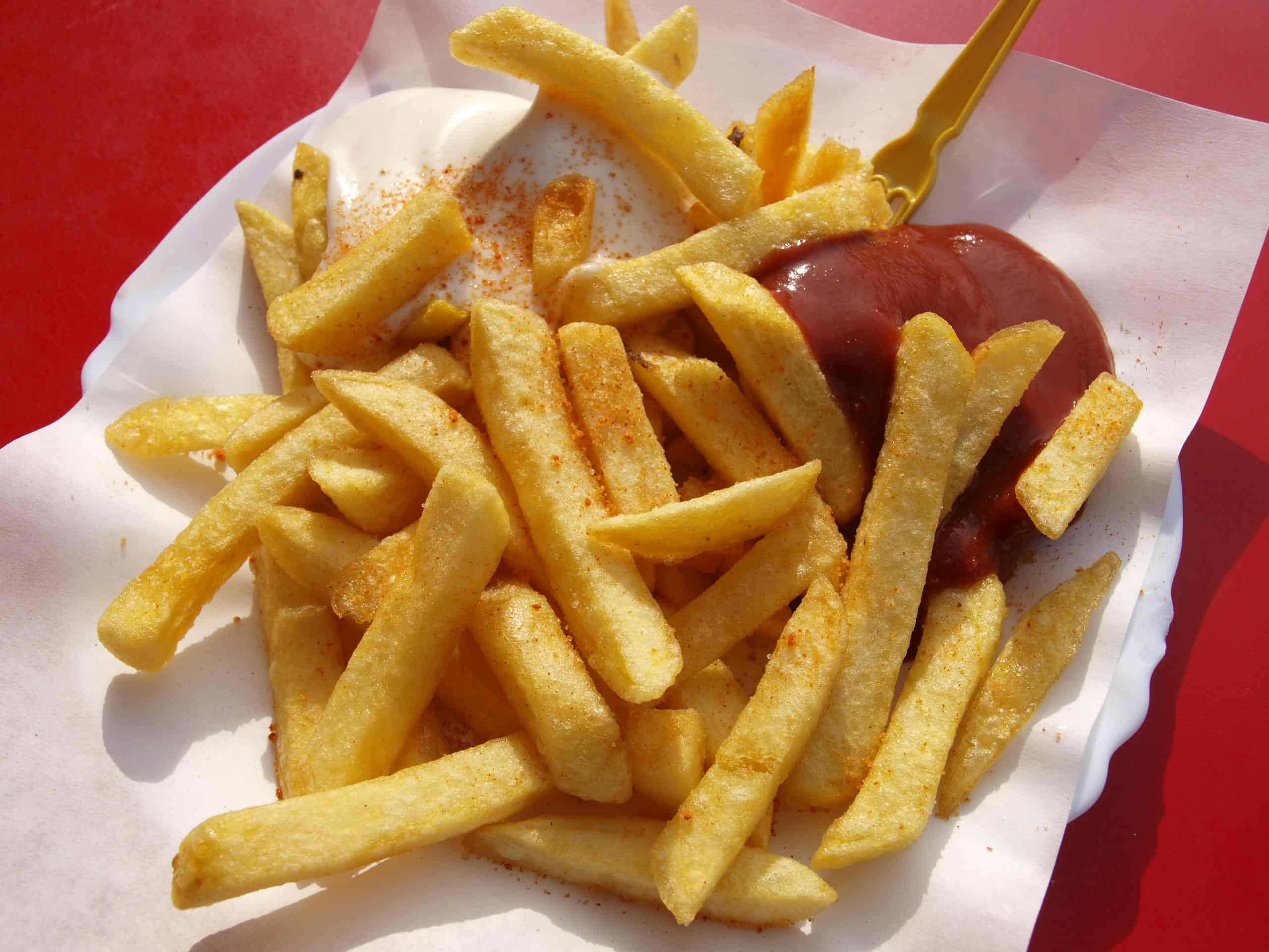 Delicious crispy French fries served with ketchup and mayonnaise on a paper plate