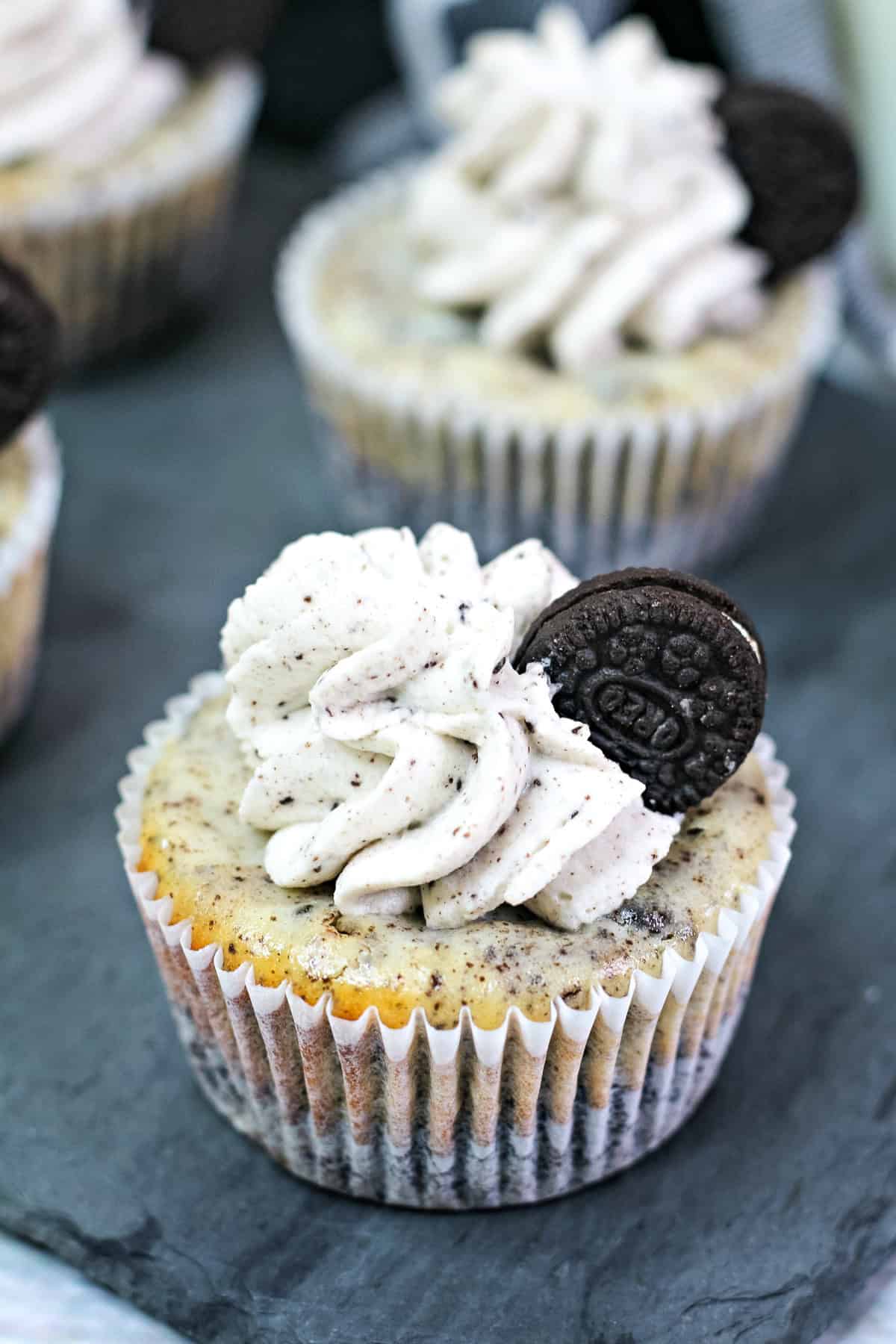 a mini Oreo cheesecake topped with Oreo whipped cream and a mini Oreo inside a cupcake wrapper.